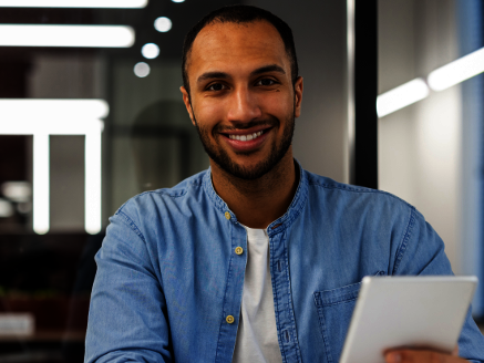 Mann mit Tablet in der Hand vor Laptop