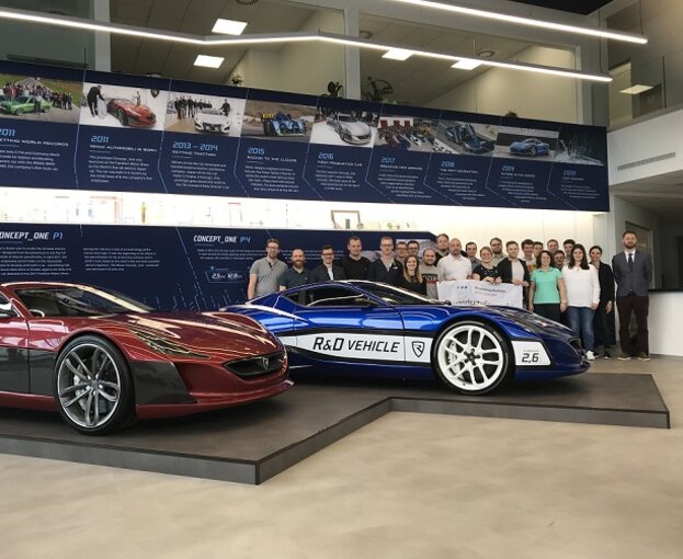 Studierende bei der Firma Rimak hinter einem Rennwagen