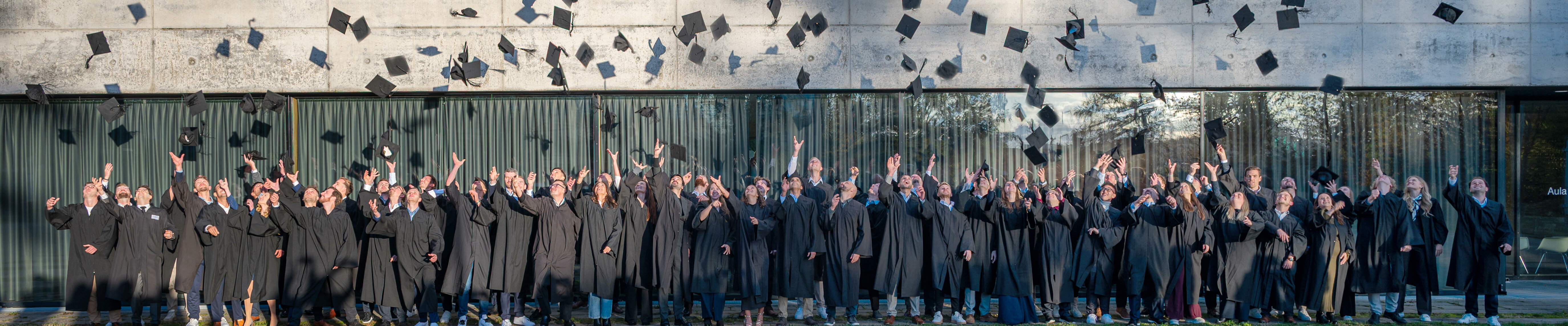 Studienabsolventen, die Ihre Akademikerhüte vor der Aula der Hochschule Aalen in die Höhe werfen