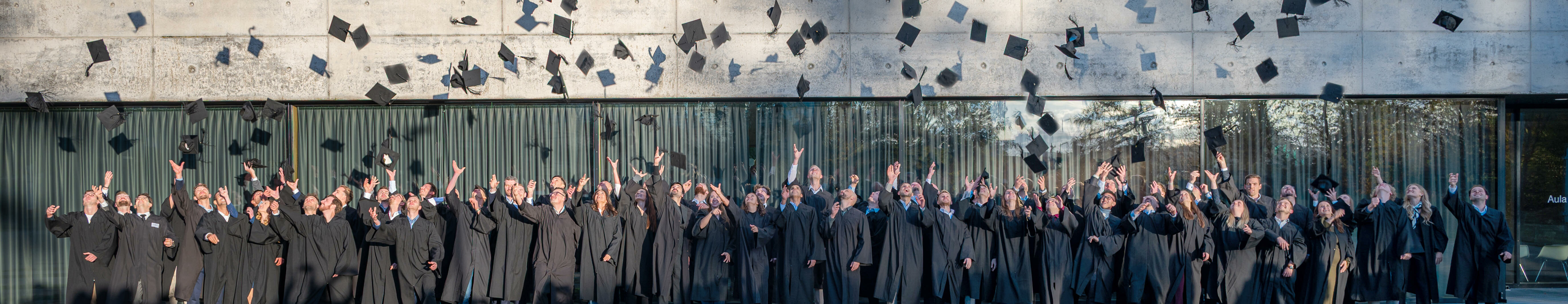 Studienabsolventen, die Ihre Akademikerhüte vor der Aula der Hochschule Aalen in die Höhe werfen