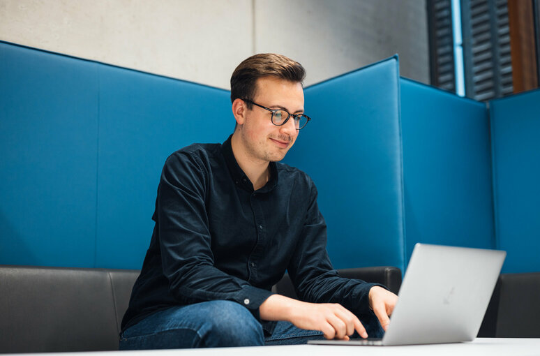 Student am Laptop in Sitzecke