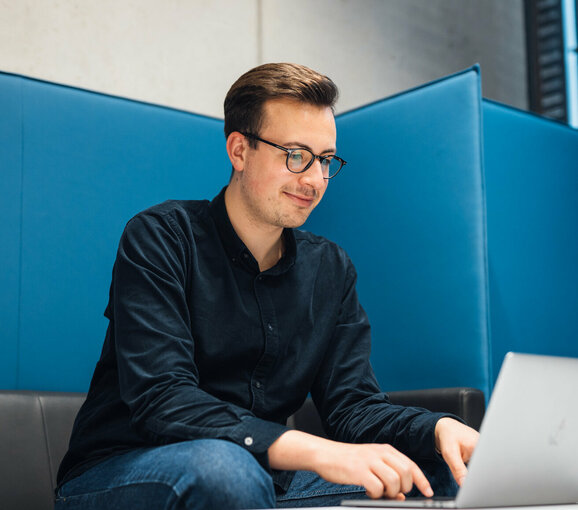 Student am Laptop in Sitzecke