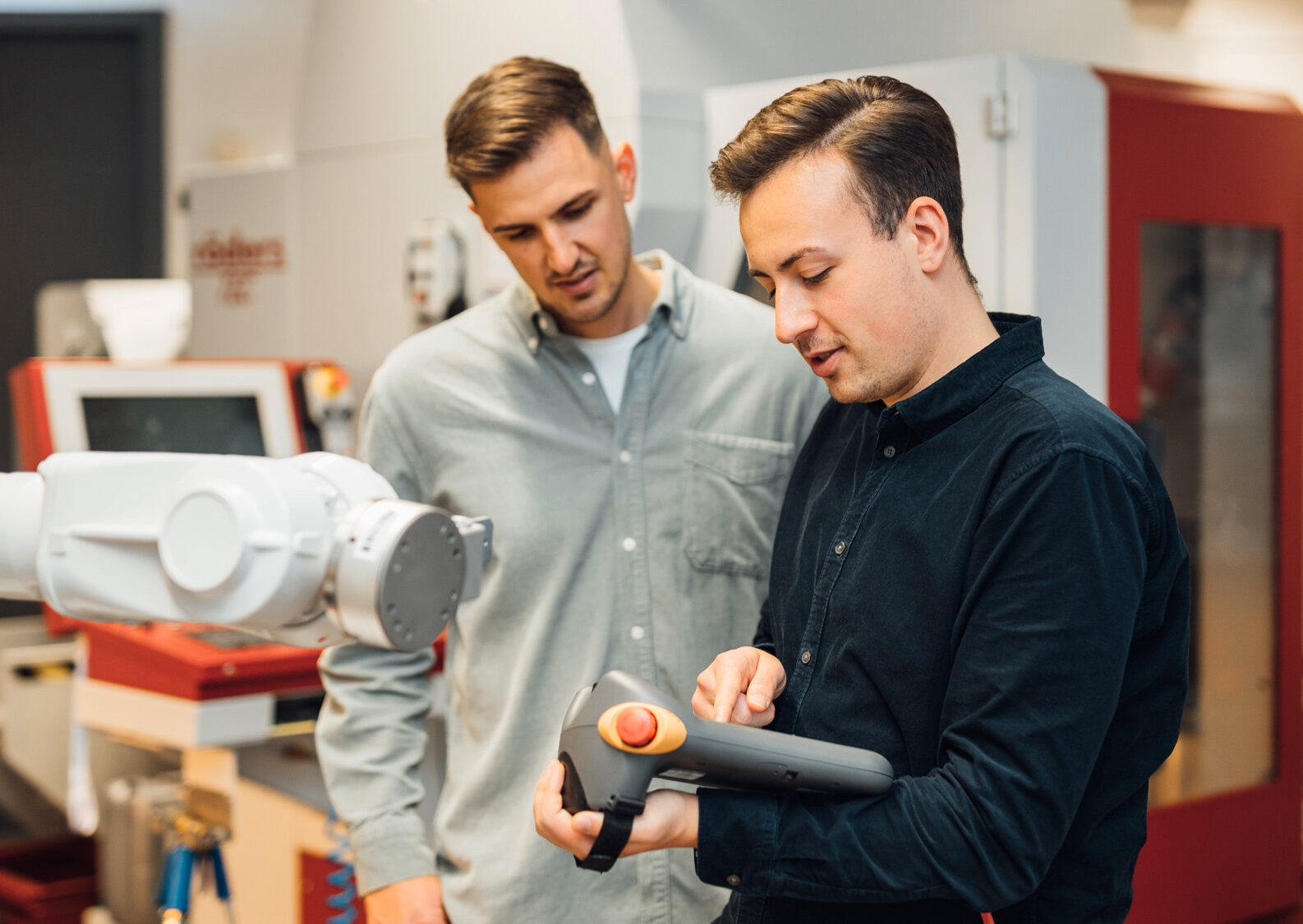 Studierende in einem technischen Umfeld mit Roboterarm